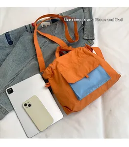 Détail du cabas orange avec poche bleue comparé à un iPad et un téléphone pour la taille