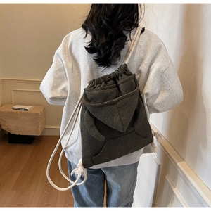 Detail of dark plaid drawstring bucket bag showing textured fabric and rope strap