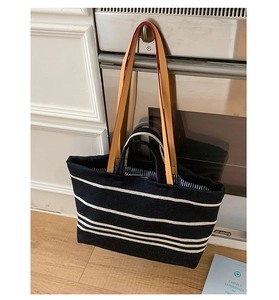 Detail of canvas tote bag with brown leather handles and striped lining in a kitchen set