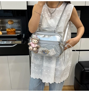 Detailed view of silver PVC crossbody bag with clear window and plush charm accessory