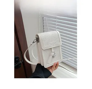 Close-up of white woven mini crossbody bag featuring an elegant heart metal charm