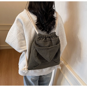 Detail of dark green checkered bucket bag showing thick cream cotton drawstrings and texture