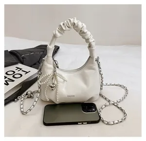 Detailed view of white pleated dumpling bag with pearl bow and metal chain strap