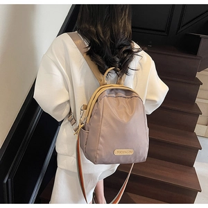 Detail of lavender nylon backpack featuring colorful striped straps and camel leather trim