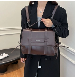 Detail of soft leather crossbody bag featuring front decorative straps and bow side details