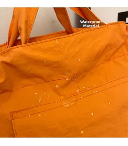 Gros plan du tissu en nylon orange imperméable d'un cabas avec gouttes d'eau