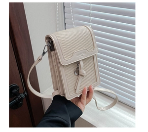 Detail of cream woven crossbody bag with leather trim and knotted metal charm
