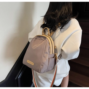 Close-up of mini nylon backpack featuring rainbow striped straps and leather handle