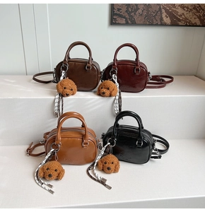 Detailed close-up of four mini leather crossbody bags with plush dog charms and brand logo