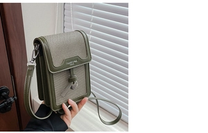 Detail of forest green square crossbody bag with textured fabric and flap closure