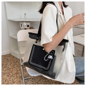Détail du sac cabas transparent en PVC avec poignées en cuir noir et breloque ours