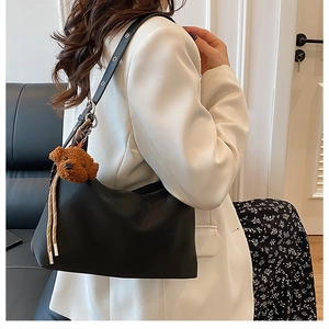 Détail du sac hobo noir en similicuir avec œillets argentés et charm ours en peluche