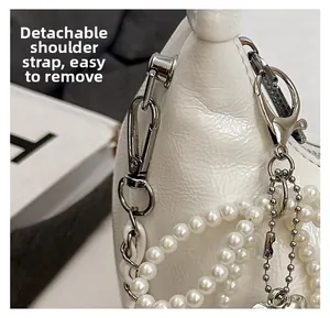 Detail view of white leather bag with detachable silver metal hooks and pearl chain strap