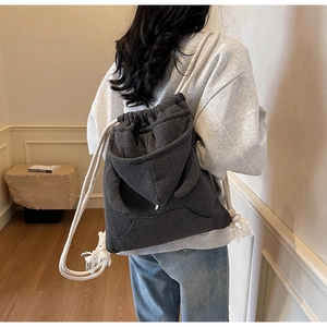 Close-up of waffle texture fabric and hoodie-style pocket on a grey drawstring bucket bag