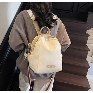 Detailed back view of a cream white mini nylon backpack with striped woven shoulder straps