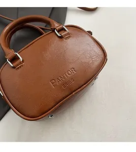 Detail of brown vintage oil-wax leather handbag showing embossed logo and dual handles