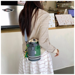 Detail of checkered drawstring bucket bag showing contrast colors and woven strap