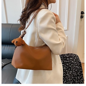 Gros plan du sac hobo en cuir marron avec bandoulière réglable et breloque ours