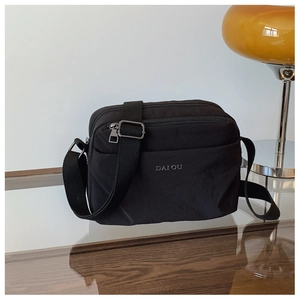 Close-up of black nylon crossbody bag featuring multiple zipper pockets and DAIOU logo
