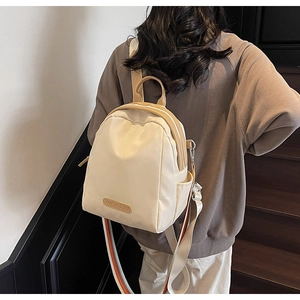 Detailed back view of a minimalist beige nylon backpack on model showing colorful straps