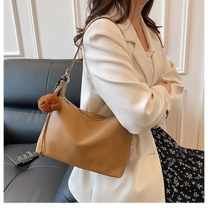 Détail du sac porté épaule sac beige avec une texture mate et un joli pendentif ours en peluche