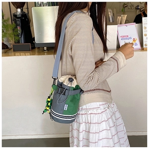 Detail of checkered cycling bucket bag with drawstring closure and colorful beaded charm