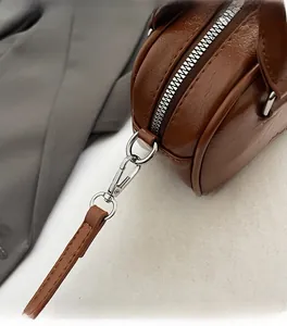 Detail of dark brown leather handbag featuring silver metal zipper and fine hardware textures
