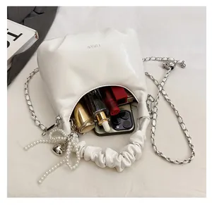Detailed view of white pleated dumpling bag with silver chain and pearl heart charm