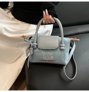 Detail of light blue denim handbag with cute puppy embroidery and adjustable strap