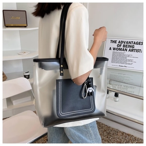 Détail du sac cabas en PVC transparent avec bordure en cuir noir et breloque panda