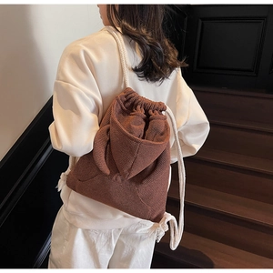 Close-up of rabbit ear detail and drawstring closure on brown checkered bucket bag