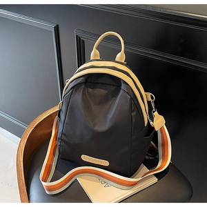 Detail of black nylon backpack with beige leather handles and striped fabric strap