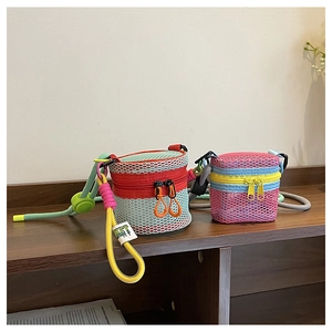 Detail of colorful hollow mesh mini crossbody bags with braided straps on wooden surface