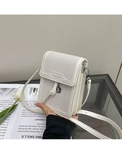 Macro view of cream white square crossbody bag with textured patchwork and decorative knot