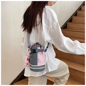 Detail view of plaid cylinder bike bag with drawstring and pink flower charm pendant