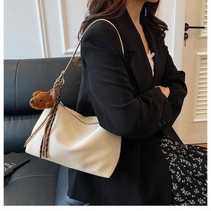 Détail du sac hobo blanc cassé avec texture cuir et pendentif ours en peluche marron