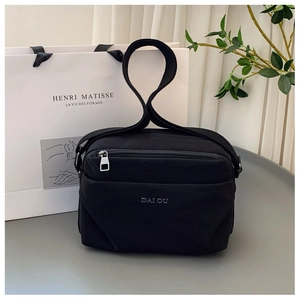 Detail view of durable black nylon crossbody bag featuring stylish letter print and strap