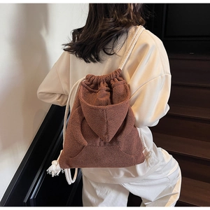 Detail of brown waffle texture backpack featuring unique hoodie cap and white rope straps