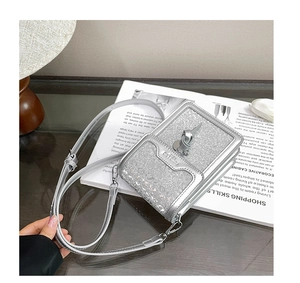 Detail of silver sequin crossbody phone bag featuring a top flap and adjustable strap