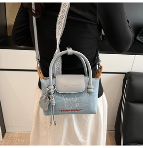 Detail of denim crossbody bag featuring white puppy embroidery and adjustable strap