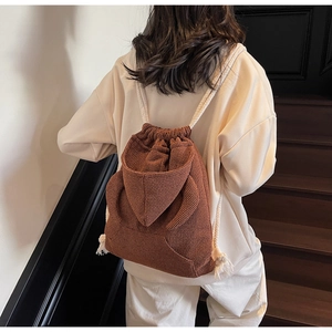 Detail of waffle-textured dark brown drawstring backpack with playful animal ear accents