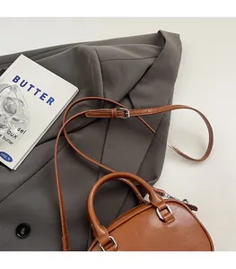 Detail of a brown leather handbag on a grey suit with a silver metal clasp
