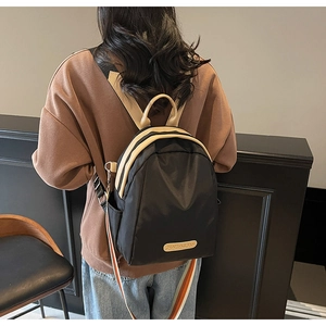 Detail of black nylon backpack with khaki trim and a colorful striped shoulder strap