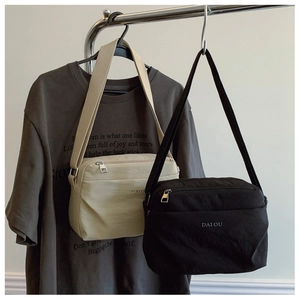 Detail of minimalist canvas crossbody bags in black and beige with adjustable straps