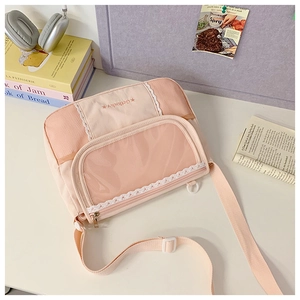 Pink canvas crossbody bag featuring lace trim and clear mesh pocket on a desk setting