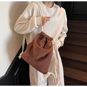 Detail of brown waffle texture knit backpack with cream drawstring and flap pocket design