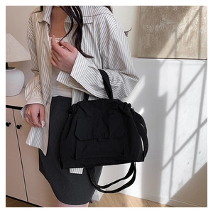 Détail du sac fourre-tout noir en nylon montrant la poche à rabat et la bandoulière