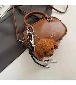 Detail of caramel brown PU leather handbag with PANTOR logo and plush teddy bear charm