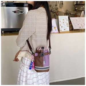 Lifestyle view of checkered drawstring bike bucket bag with purple and brown color block