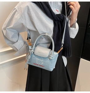 Detail view of light blue denim crossbody bag featuring white puppy embroidery and blue tassel